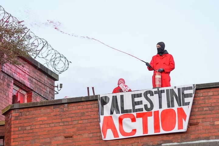 Two actionists on a roof using paint to disrupt a weapons factory.